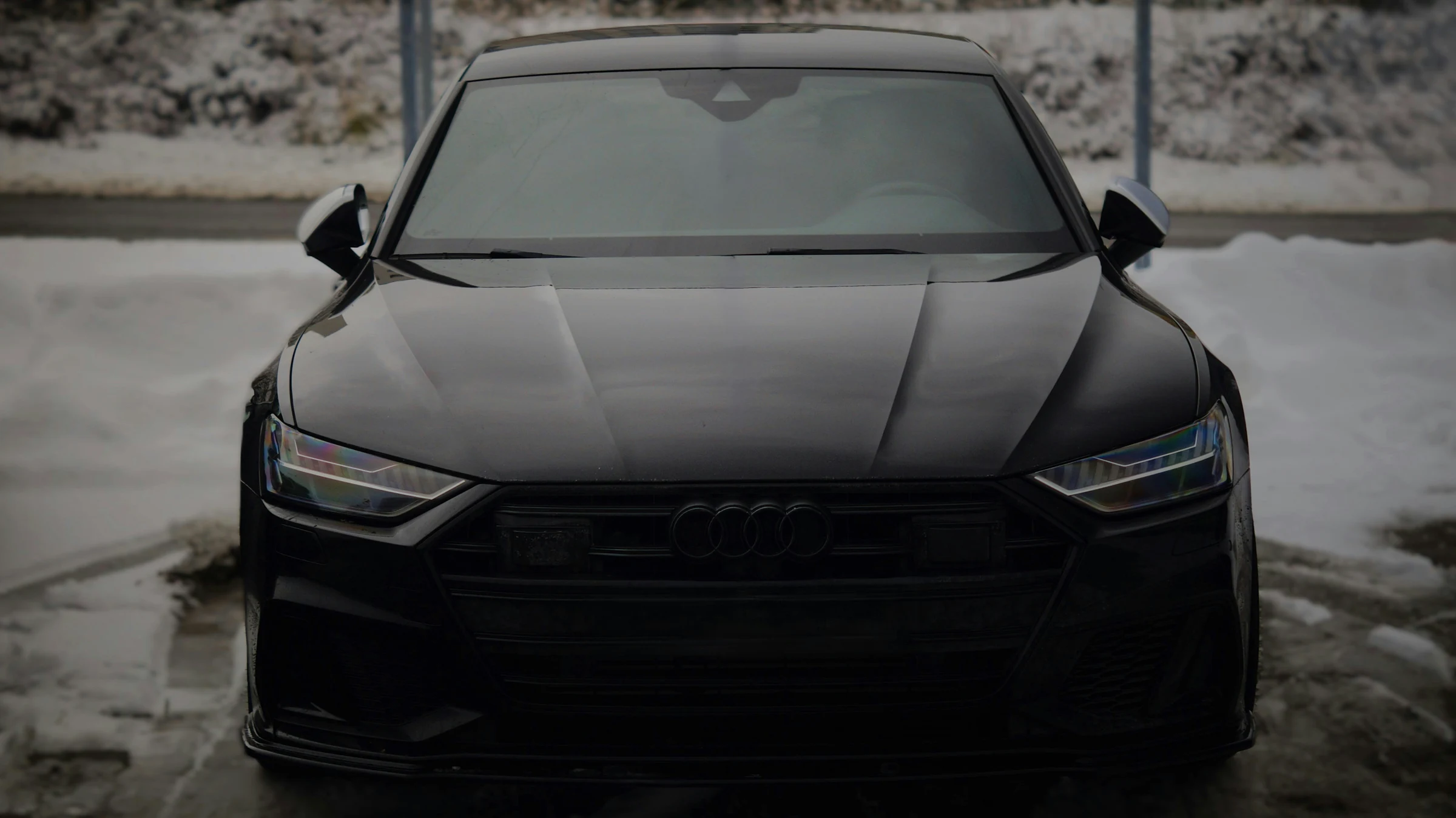 Black Audi A7 facing the camera on a snow-covered forecourt